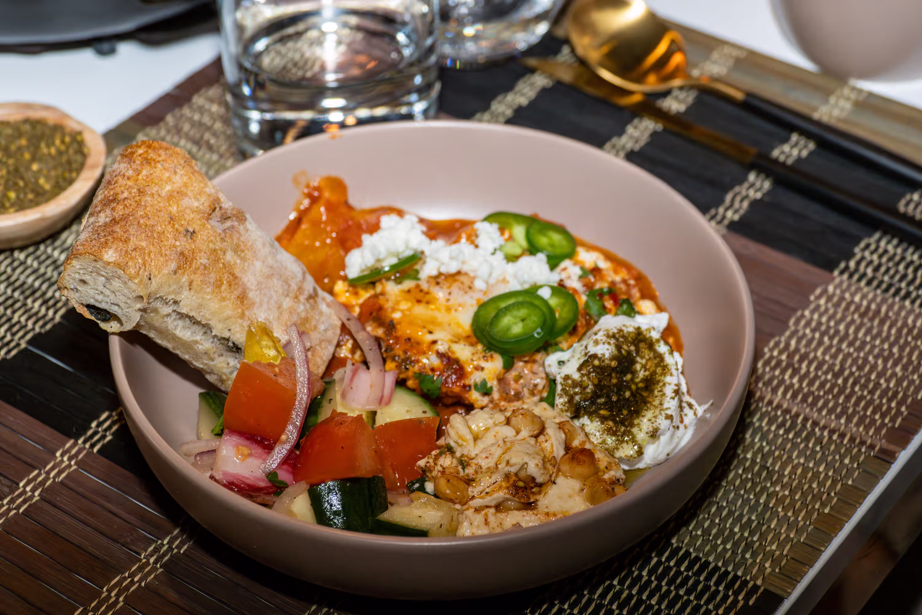 Mediterranean shakshuka dinner bowl styled with fresh bread and vegetables for food brand lifestyle photography