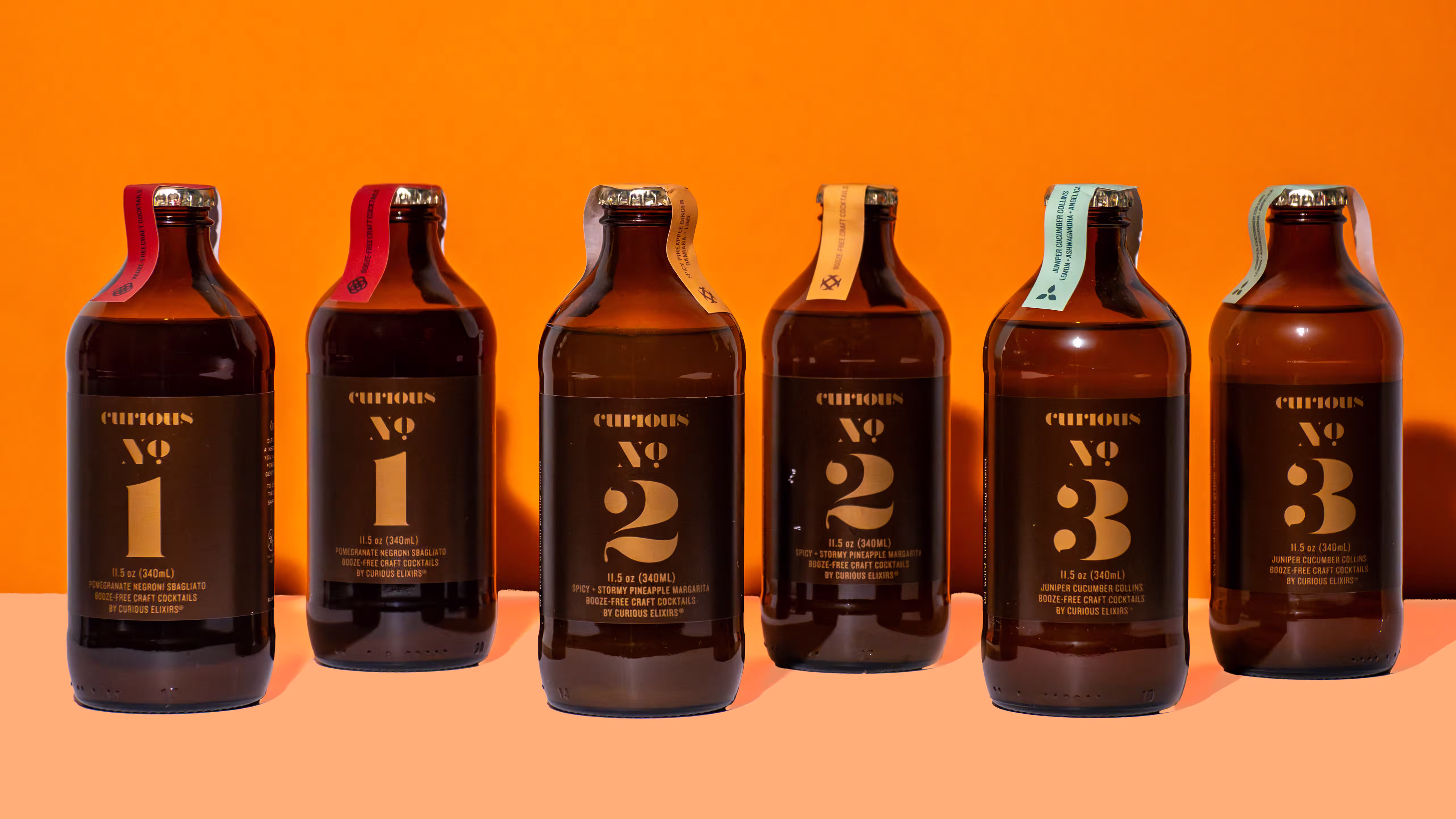 Six Curious Elixirs booze-free craft cocktail bottles lined up in a row against an orange background in a styled product photograph